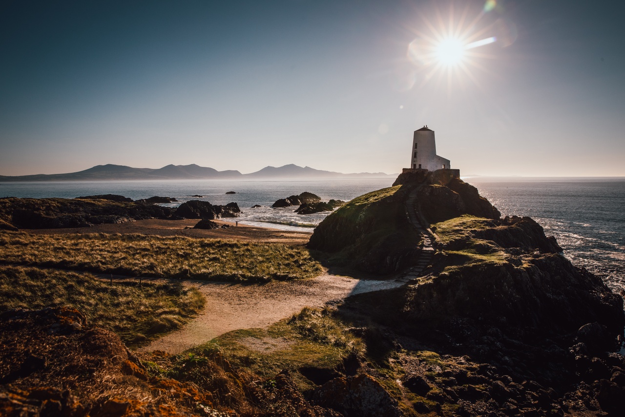 Llanddwyn beach lighthouse in the sunshine with Eryri mountains in the background.