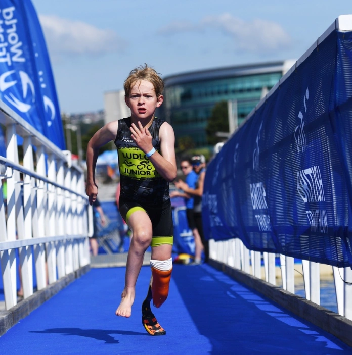 Bachgen yn cymryd rhan yn Aquathlon Go Tri, Abertawe, Gorllewin Cymru