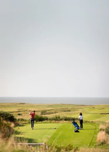 Dyn a dynes yn chwarae golff y Royal Porthcawl, De Cymru