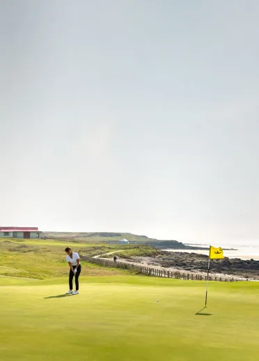 Menyw yn chwarae golff yn y Royal Porthcawl, De Cymru