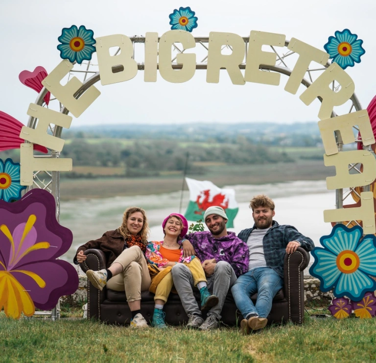 pobl yn eistedd o dan fwa gwyl Big Retreat