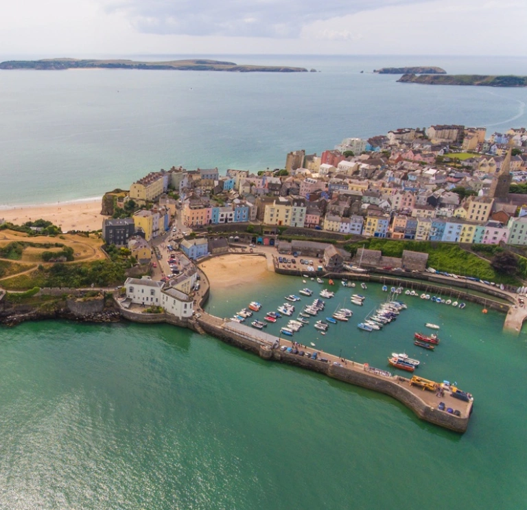 Yr olygfa wrth edrych i lawr ar yr harbwr, y castell a’r traeth yn Ninbych-y-Pysgod