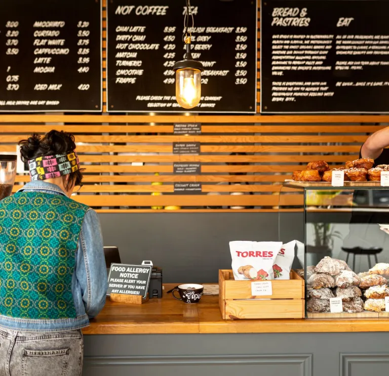 Gwraig yn cael ei gweini yn y Alex Gooch Bakery, Ffordd yr Eglwys Newydd, Caerdydd.