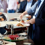 Business clients serving themselves at a food buffet.