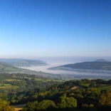 Golygfa o Fannau Brycheiniog o Llangyndir, gyda niwl yn ddwfn yn y cwm.
