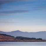 Golygfa tesog o Lyn Trawsfynydd a mynyddoedd Eryri yn y cefndir.