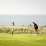 Menyw yn chwarae golff yn y Royal Porthcawl, De Cymru