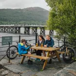 Teulu gyda beiciau yn eistedd wrth fainc bicnic, Llwybr Mawddach
