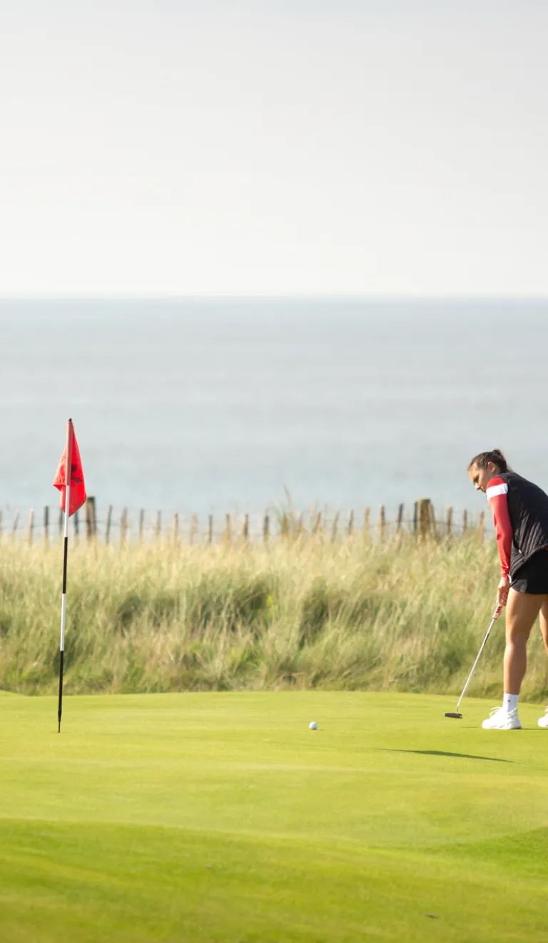 Menyw yn chwarae golff yn y Royal Porthcawl, De Cymru